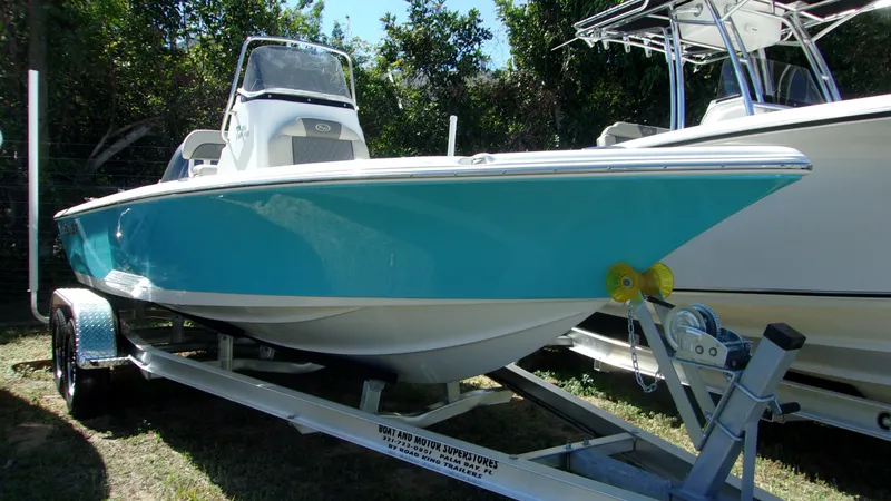 Slide: The Image of 2025 Key West 210 Bay Reef boat on trailer, turquoise hull, parked outdoors. - 0