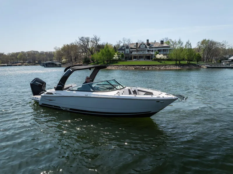Slide: The Image of 2025 Monterey 275 SS Bowrider cruising on a serene lake near a luxurious waterfront home. - 5