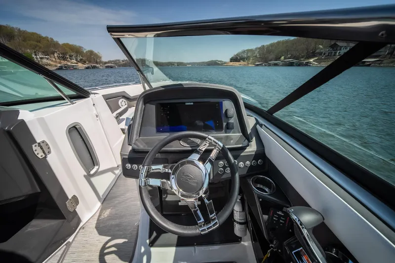 Slide: The Image of 2025 Monterey 275 SS Bowrider dashboard with steering wheel, on a scenic lake. - 9