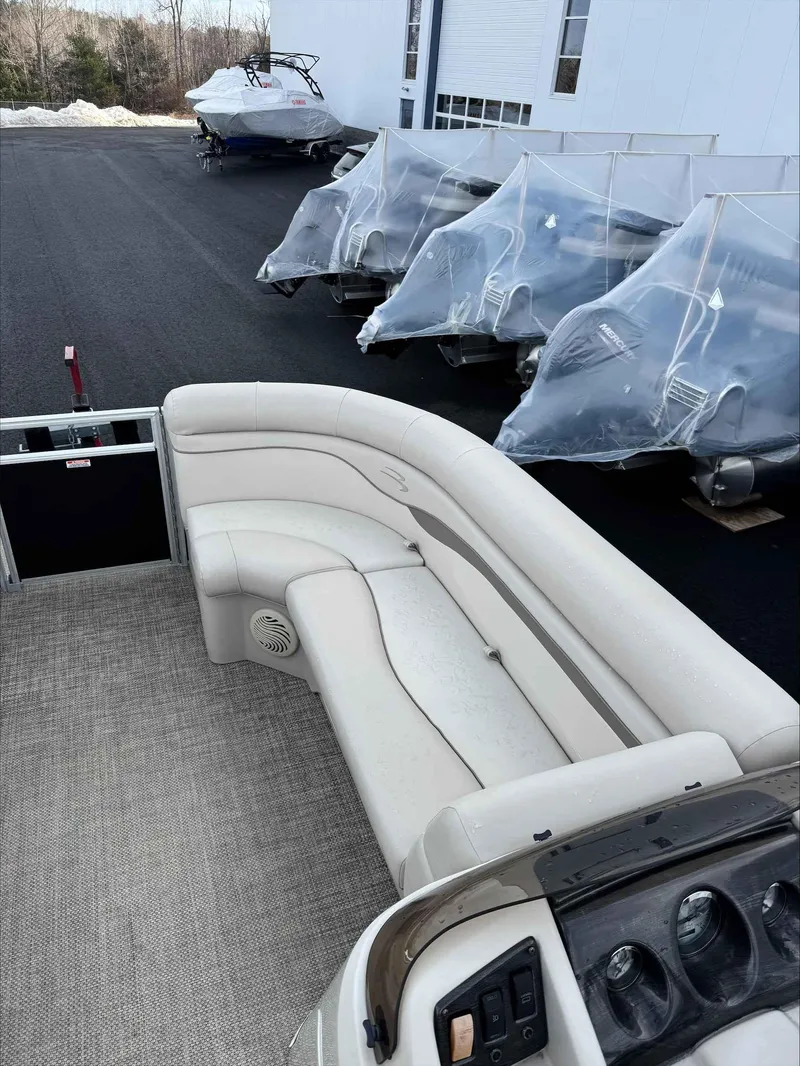 Slide: The Image of 2016 Bennington 22SLXP pontoon boat with beige seating, parked near covered boats. - 11