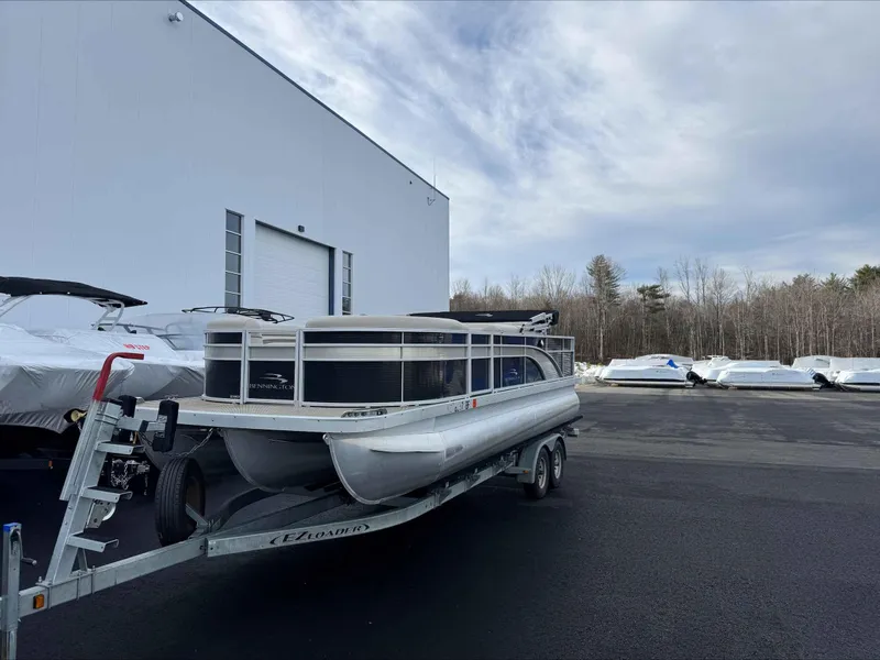 Slide: The Image of 2016 Bennington 22SLXP pontoon boat on trailer, parked near a large building. - 5