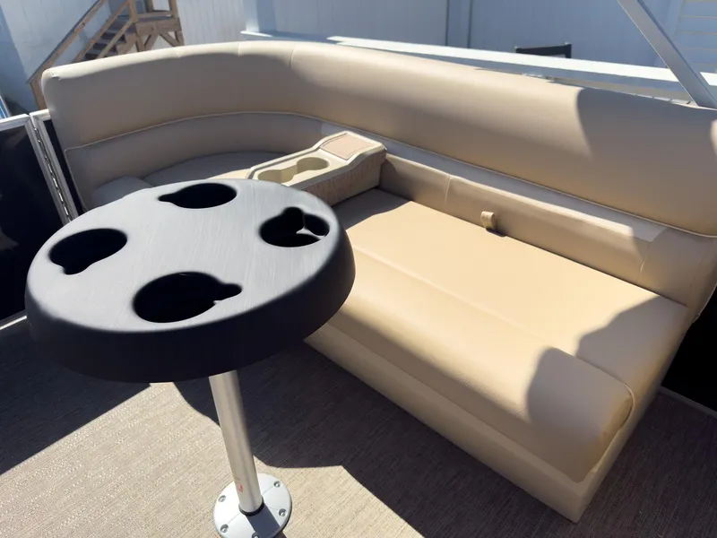Slide: The Image of 2025 Godfrey Sweetwater Xperience 22' Tritoon interior with beige seating and cup holder table. - 24