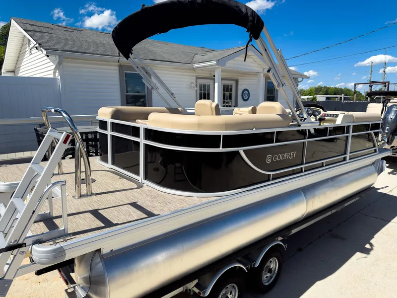 Slide: The Image of 2025 Godfrey Sweetwater Xperience 22' Tritoon with split bench, parked on trailer. - 3