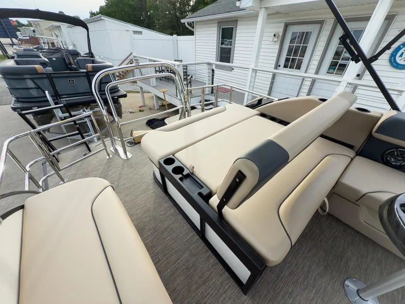 Slide: The Image of 2025 Godfrey Sweetwater 22' Tritoon with flip lounge seating, docked near a white building. - 20