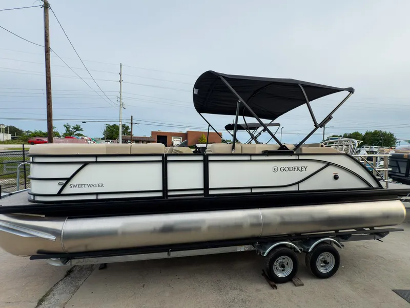 Slide: The Image of 2025 Godfrey Sweetwater 22' Flip Lounge Tritoon on trailer, featuring sleek design and canopy. - 3