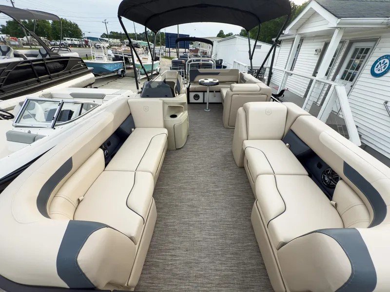 Slide: The Image of 2025 Godfrey Sweetwater 22' Tritoon with spacious seating and modern design at a marina. - 5