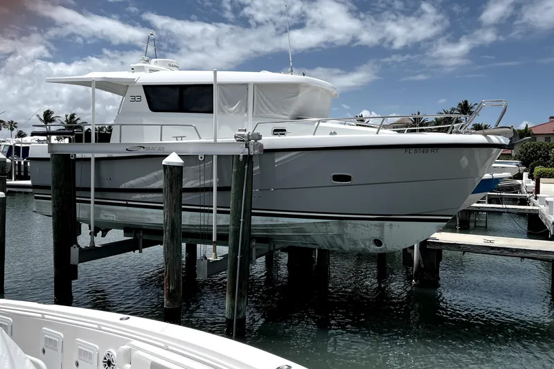Slide: The Image of 2019 Sargo 33 All Season boat docked on a lift under a partly cloudy sky. - 3