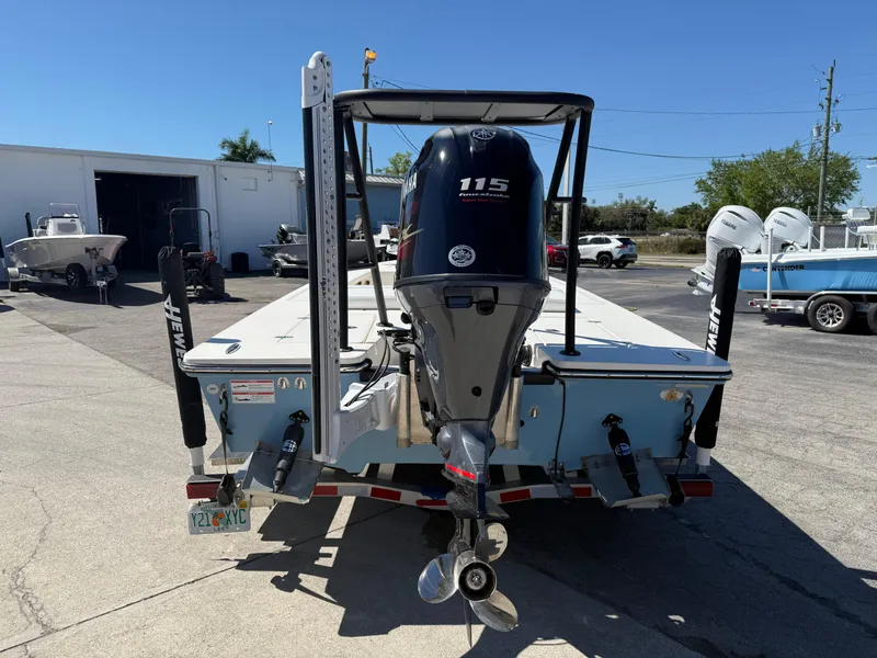 Slide: The Image of 2024 Hewes 18 Redfisher boat with Yamaha 115 engine, parked outdoors. - 5