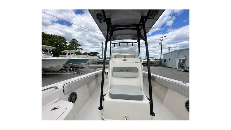 Slide: The Image of 2024 Sea Chaser 23 LX boat interior with seating and T-top under a cloudy sky. - 16