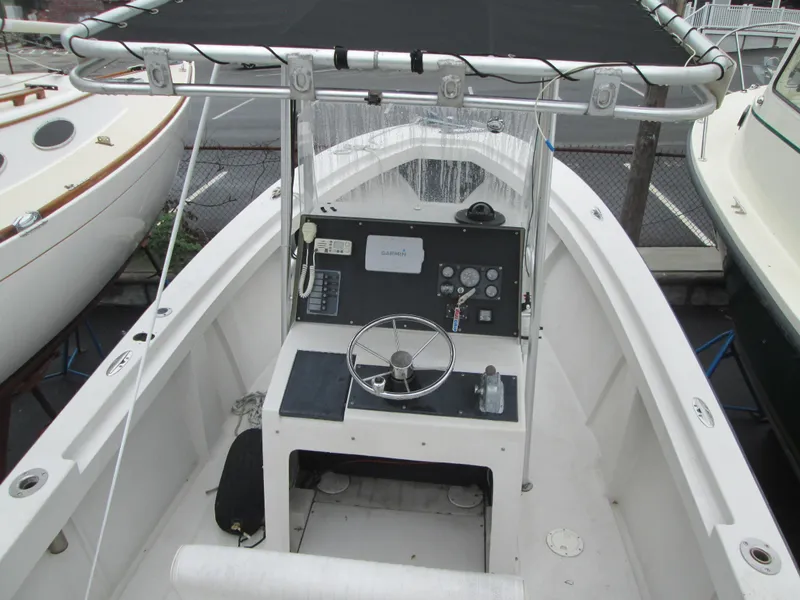Slide: The Image of 1977 SeaCraft SF 23 IO boat with center console and steering wheel, docked in a marina. - 2