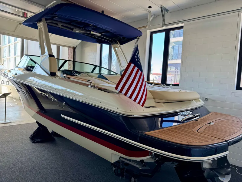 Slide: The Image of 2025 Chris-Craft Sportster 25 boat with American flag, displayed indoors. - 24