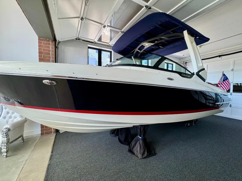 Slide: The Image of 2025 Chris-Craft Sportster 25 boat in garage, featuring sleek design and blue canopy. - 25