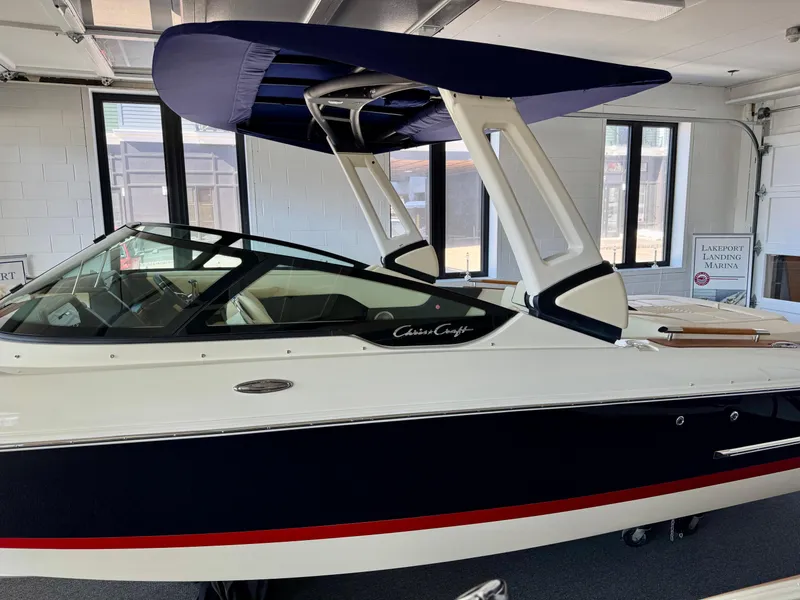 Slide: The Image of 2025 Chris-Craft Sportster 25 boat in showroom, featuring sleek design and modern canopy. - 26