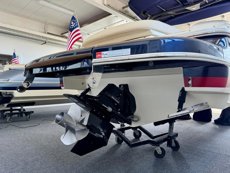 Slide: The Image of 2025 Chris-Craft Sportster 25 boat in showroom, featuring sleek design and American flag. - 27