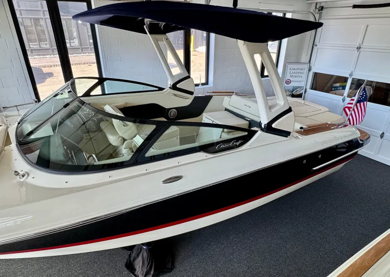 Slide: The Image of 2025 Chris-Craft Sportster 25 boat with sleek design and American flag in showroom. - 4