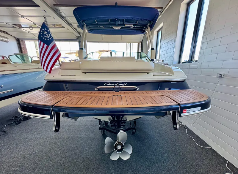 Slide: The Image of 2025 Chris-Craft Sportster 25 boat with wooden deck and American flag in showroom. - 6
