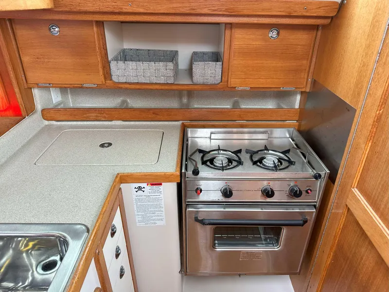 Slide: The Image of Catalina 34 MkII 2007 yacht kitchen with stove, oven, and wooden cabinetry. - 14
