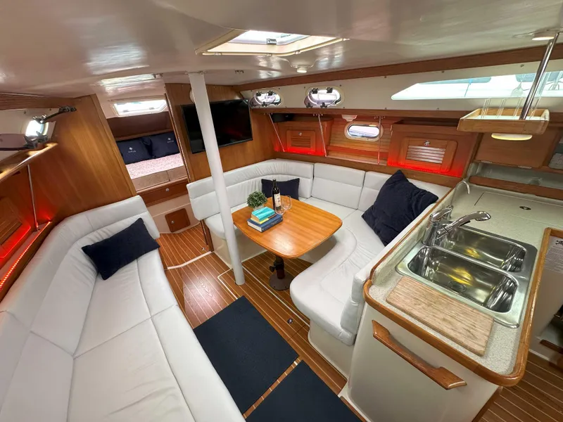 Slide: The Image of Interior of 2007 Catalina 34 MkII sailboat with white seating, wooden table, and kitchenette. - 21