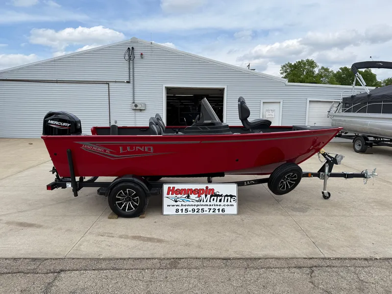 The Image of 2025 Lund 1650 Rebel XL SS boat in red on a trailer outside a marine shop. - 0