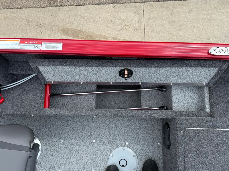 Slide: The Image of 2025 Lund 1650 Rebel XL SS boat interior with storage compartment and red trim. - 20