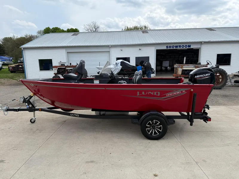 Slide: The Image of 2025 Lund 1650 Rebel XL SS boat in red, parked outside a showroom. - 3