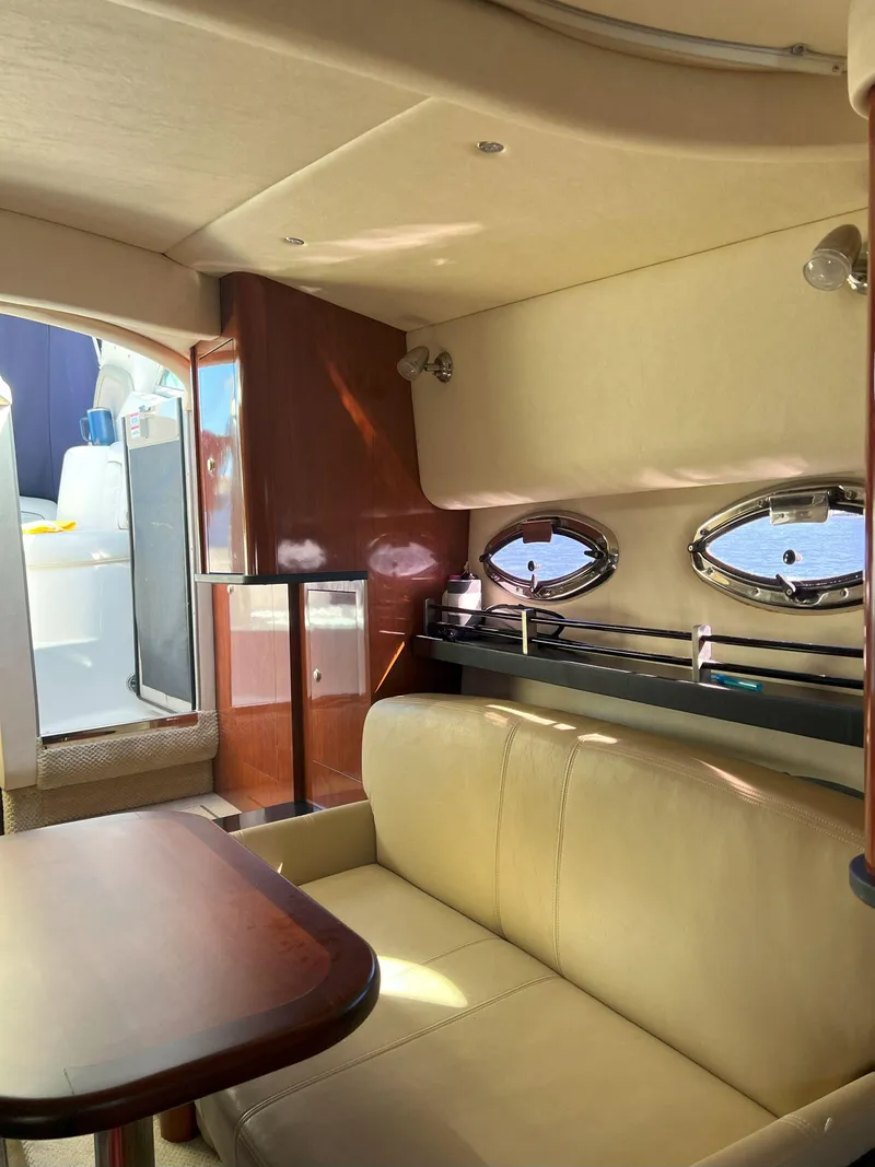 Slide: The Image of Interior of 2007 Sea Ray 290 Sundancer yacht with beige seating and porthole windows. - 19
