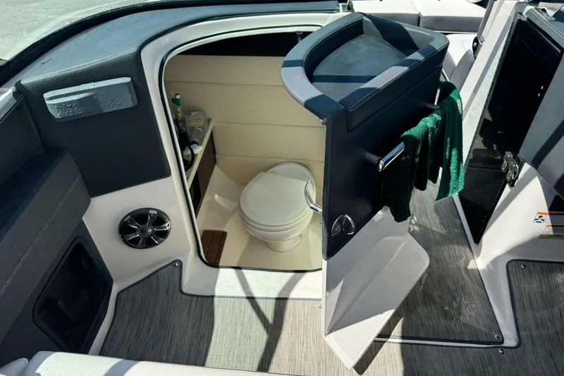 Slide: The Image of 2018 Regal 29 OBX boat interior with open door revealing compact bathroom. - 15