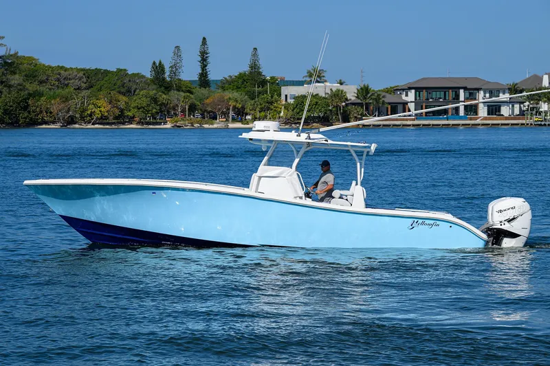 Slide: The Image of 2019 Yellowfin 34 Center Console boat on calm water, with scenic shoreline background. - 0