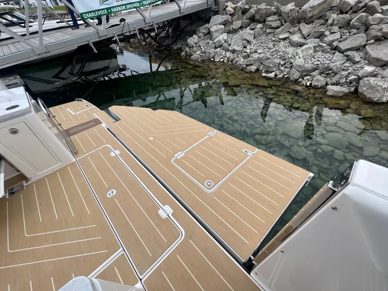 Slide: The Image of 2026 Regal 50 SAV boat deck near rocky shoreline and dock. - 6