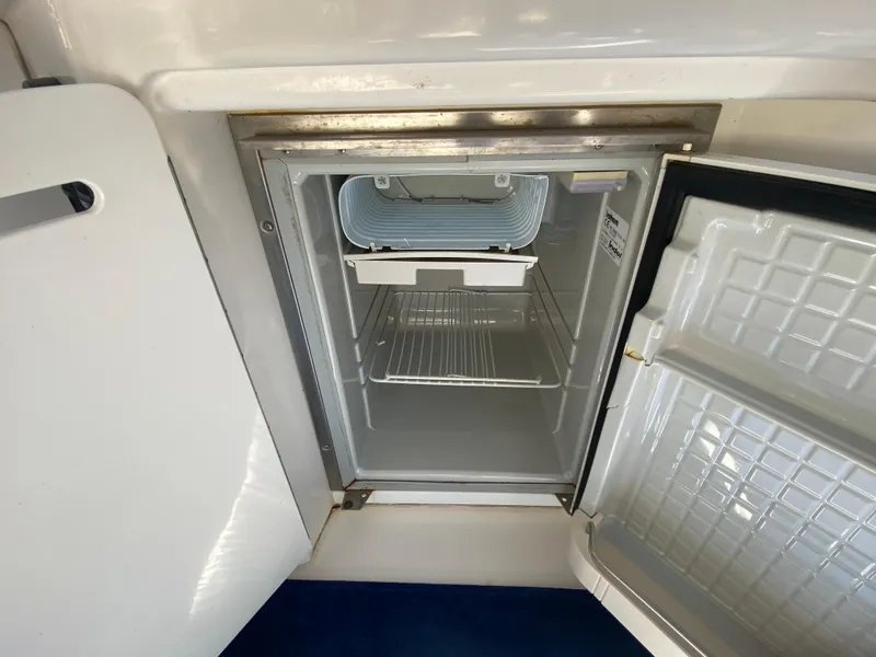 Slide: The Image of Open refrigerator on 2003 Sea Ray 340 Sundancer boat, showcasing interior storage space. - 10
