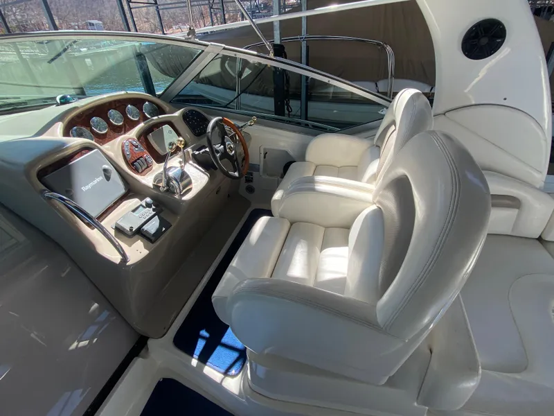 Slide: The Image of 2003 Sea Ray 340 Sundancer cockpit with dual white leather seats and wooden dashboard. - 14