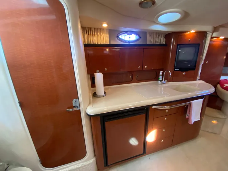 Slide: The Image of 2003 Sea Ray 340 Sundancer interior with kitchenette, wood cabinets, and sink. - 20