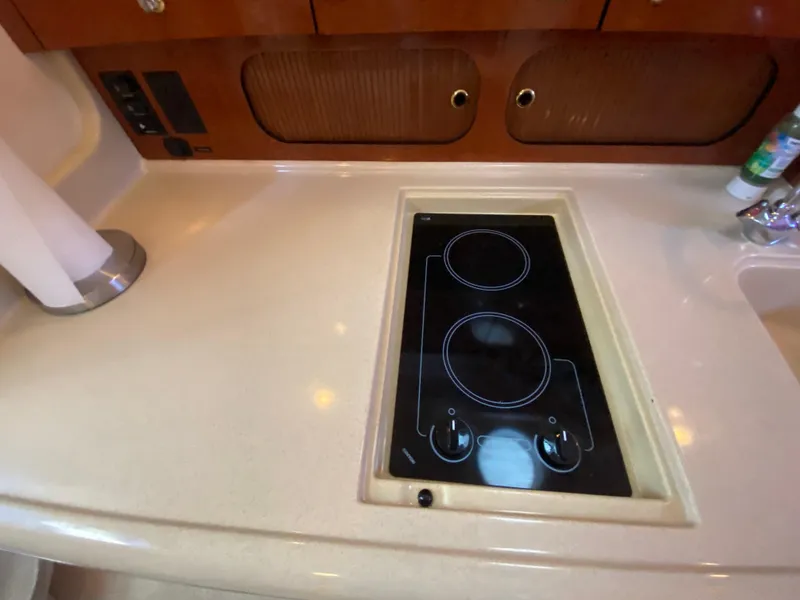 Slide: The Image of 2003 Sea Ray 340 Sundancer kitchen with built-in electric stove and wooden cabinetry. - 23