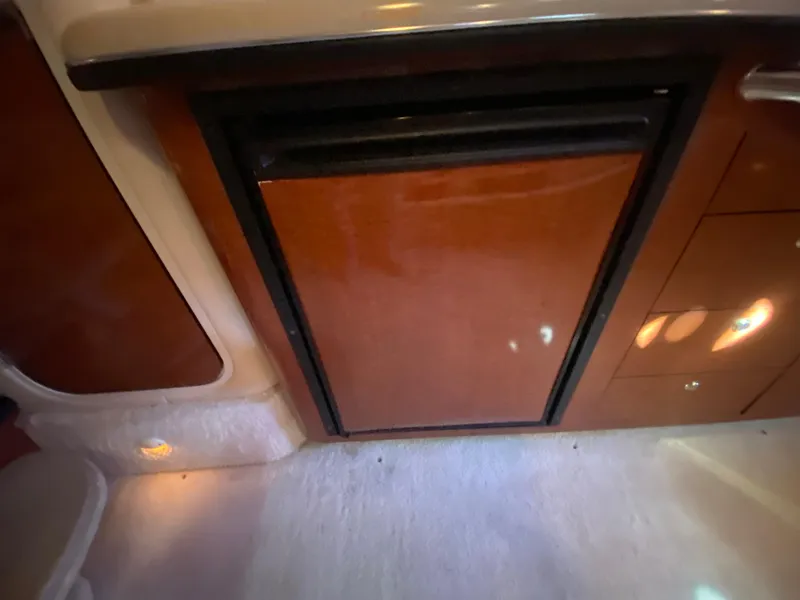 Slide: The Image of 2003 Sea Ray 340 Sundancer interior with wooden cabinetry and compact refrigerator. - 31