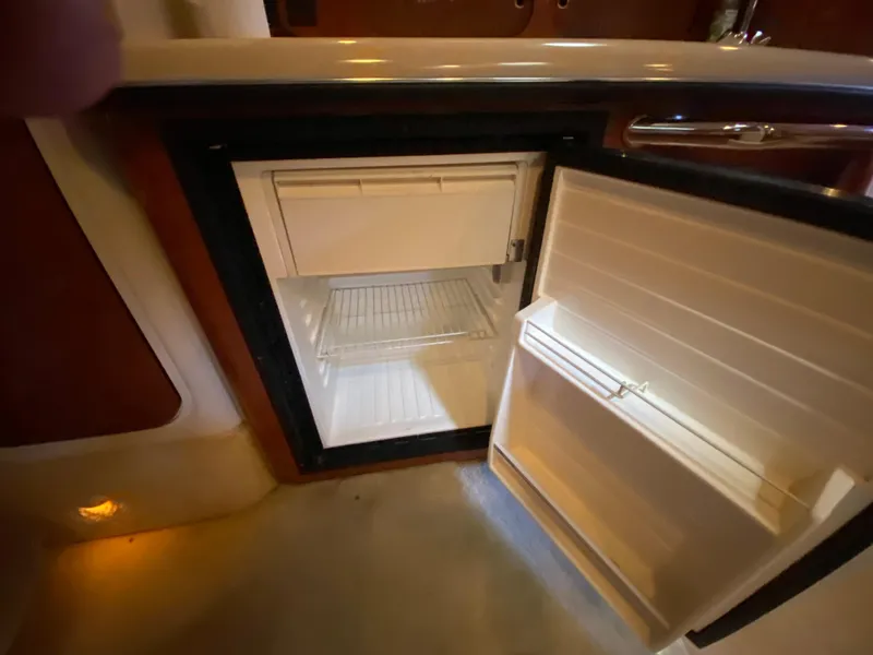 Slide: The Image of Open refrigerator inside 2003 Sea Ray 340 Sundancer yacht, showcasing interior shelving. - 32