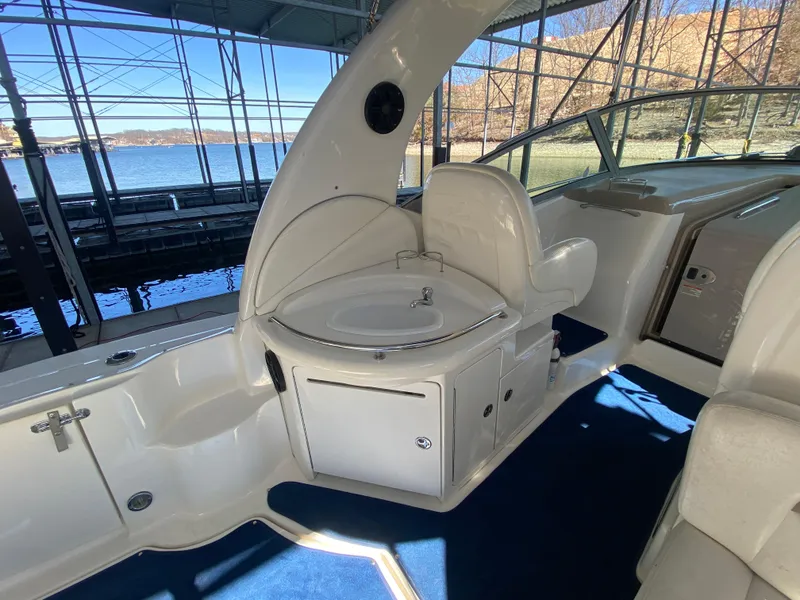 Slide: The Image of 2003 Sea Ray 340 Sundancer interior with seating and sink, docked by the water. - 8
