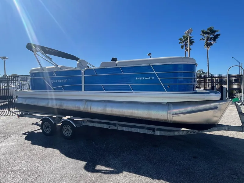 Slide: The Image of 2022 Godfrey SWEETWATER 2286 SFL pontoon boat on trailer, sunny day. - 0