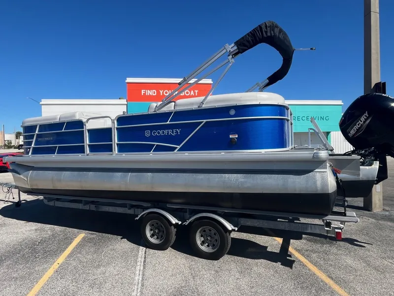 Slide: The Image of 2022 Godfrey SWEETWATER 2286 SFL pontoon boat on trailer, blue and silver design. - 1