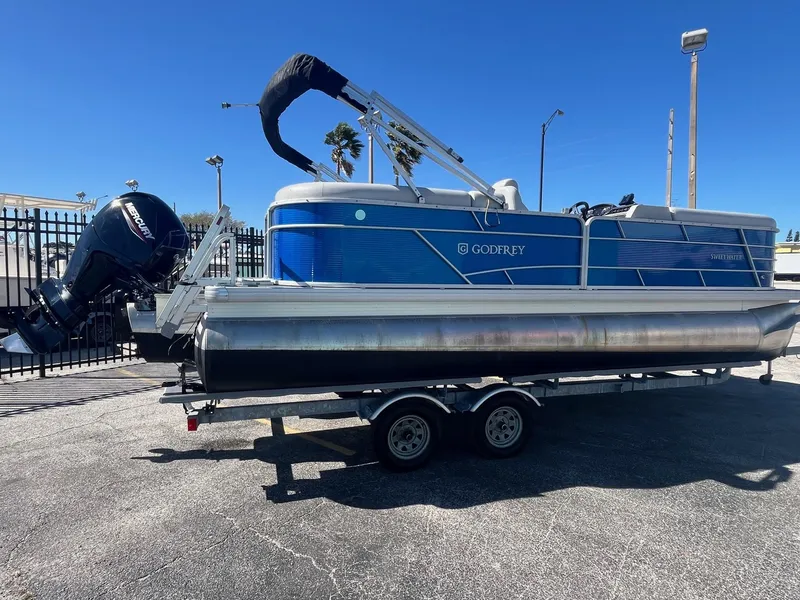 Slide: The Image of 2022 Godfrey SWEETWATER 2286 SFL pontoon boat on trailer, blue and silver design. - 4