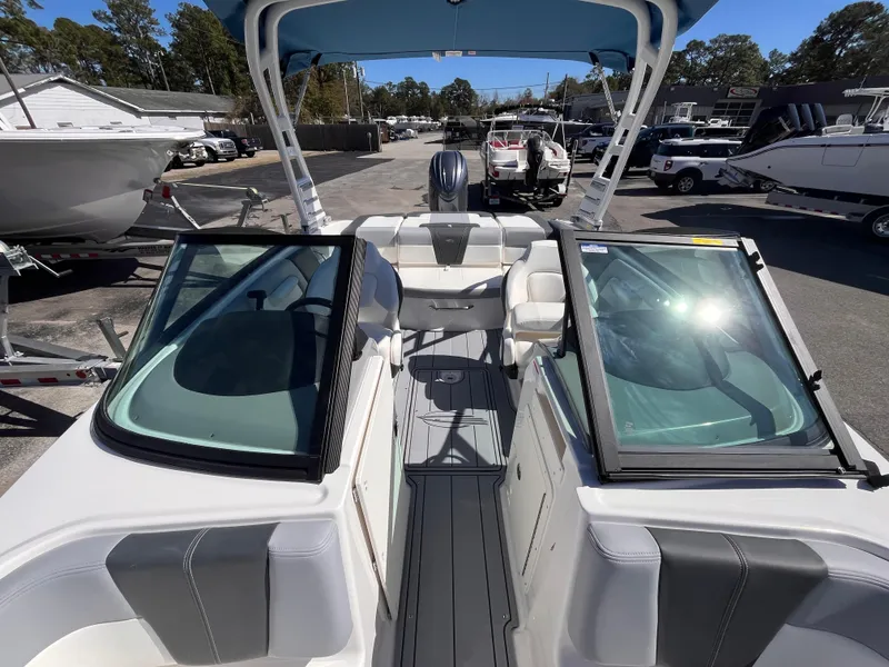 Slide: The Image of 2025 Chaparral 21 SSi OB boat interior with seating and windshield, docked outdoors. - 14