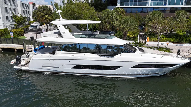 Slide: The Image of 2018 Prestige 680 yacht docked by lush greenery and modern buildings. - 10