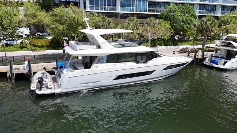 Slide: The Image of 2018 Prestige 680 yacht docked in a marina, surrounded by lush greenery. - 11