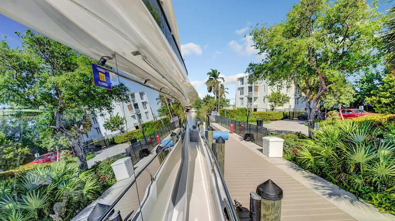 Slide: The Image of Prestige 680 yacht docked, reflecting lush greenery and modern buildings, 2018 model. - 23