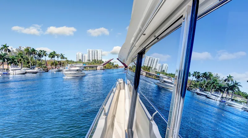 Slide: The Image of Prestige 680 yacht cruising on a sunny day, surrounded by palm trees and waterfront buildings. - 33