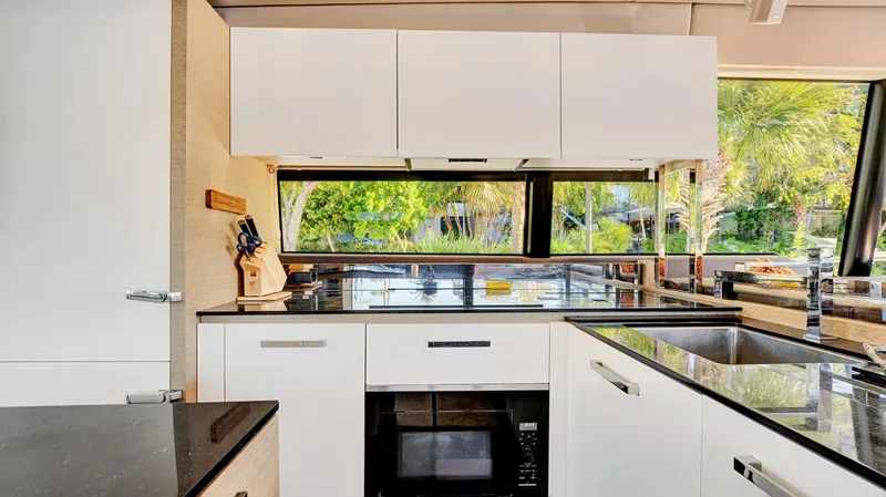 Slide: The Image of Modern kitchen interior on a 2018 Prestige 680 yacht, featuring sleek white cabinetry and large windows. - 45