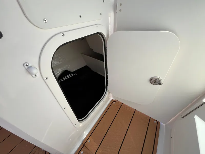 Slide: The Image of 2025 Chaparral 23 SSi OB boat storage compartment with open door on teak flooring. - 12