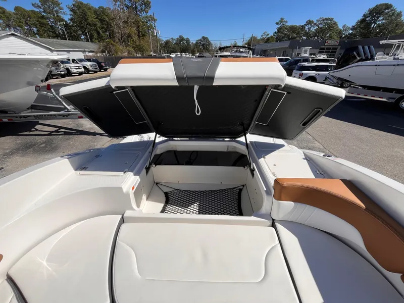 Slide: The Image of 2025 Chaparral 23 SSi OB boat interior with open storage compartment, white and tan seating. - 16