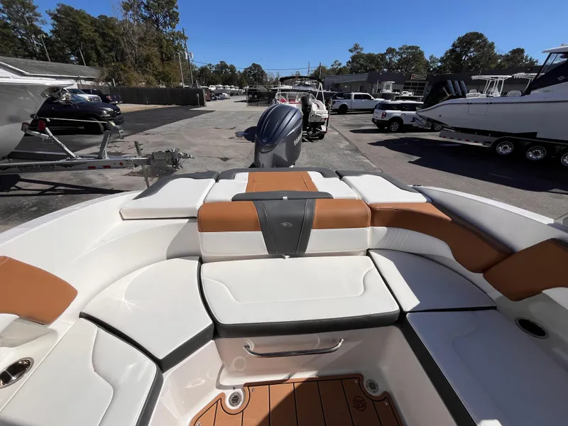 Slide: The Image of 2025 Chaparral 23 SSi OB boat interior with tan and white seating, parked outdoors. - 7