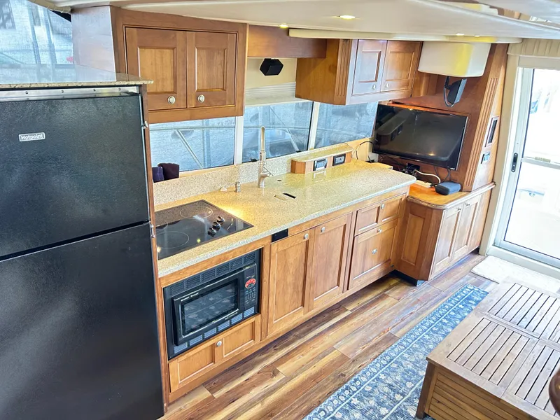 Slide: The Image of 2004 Cruisers Yachts 5000 Sedan Sport kitchen with wood cabinets, appliances, and TV. - 15