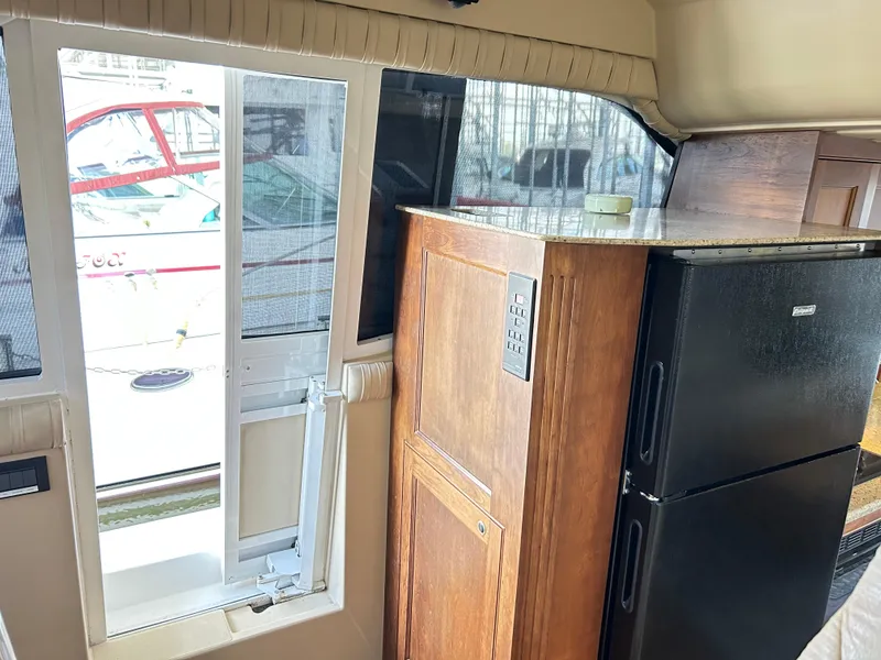 Slide: The Image of Interior of 2004 Cruisers Yachts 5000 Sedan Sport with fridge and wooden cabinetry. - 29